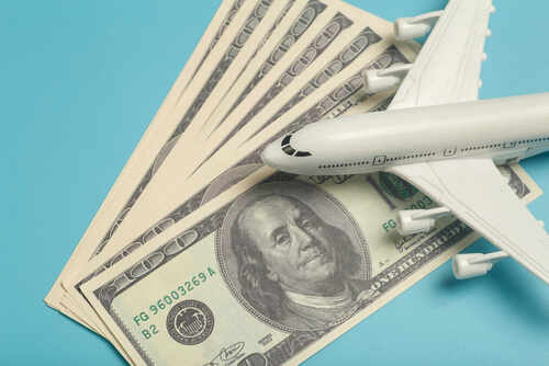 Airplane,And,Money.,Plane,On,The,Background,Of,Usa,Dollars. A model airplane placed on top of dollar bills