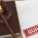 Judge’s gavel on a book beside a paper stamped guilty