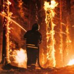 Firefighter battling a raging forest wildfire at night