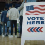 People in line next to Vote Here sign