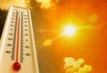 Thermometer displaying high temperature against a bright sun