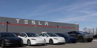 A lineup of Tesla cars parked in front of a Tesla building