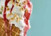 Close-up of an ice cream cone topped with strawberry sauce and chopped nuts