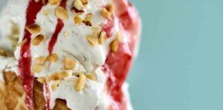Close-up of an ice cream cone topped with strawberry sauce and chopped nuts
