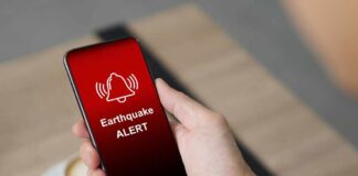 Hand holding a smartphone displaying an earthquake alert notification