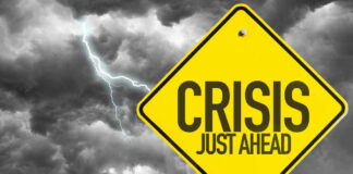 Yellow sign reading Crisis Just Ahead with stormy sky