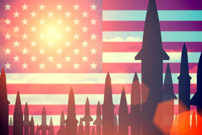 Missiles silhouetted against American flag background with sunset.