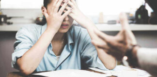 Stressed woman with hands on face at a desk.