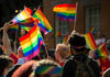 People waving rainbow flags at a pride parade.