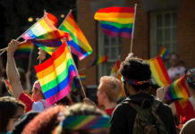 People waving rainbow flags at a pride parade.