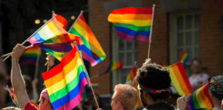 People waving rainbow flags at a pride parade.