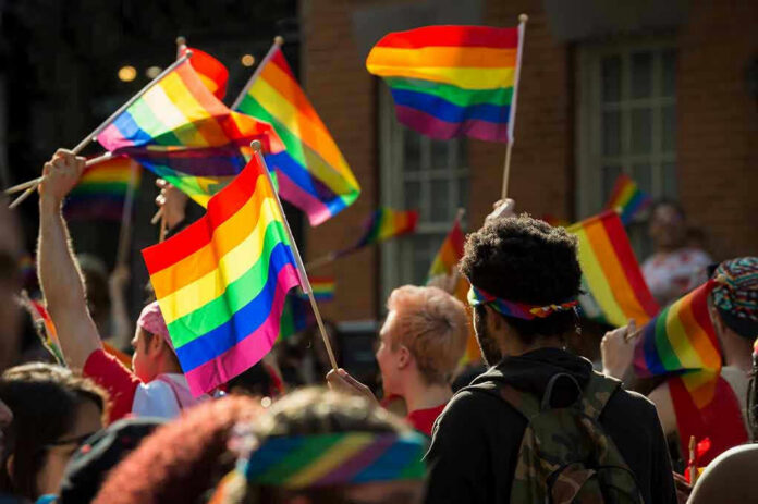 People waving rainbow flags at a pride parade.
