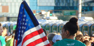 Runner with American flag at crowded outdoor event
