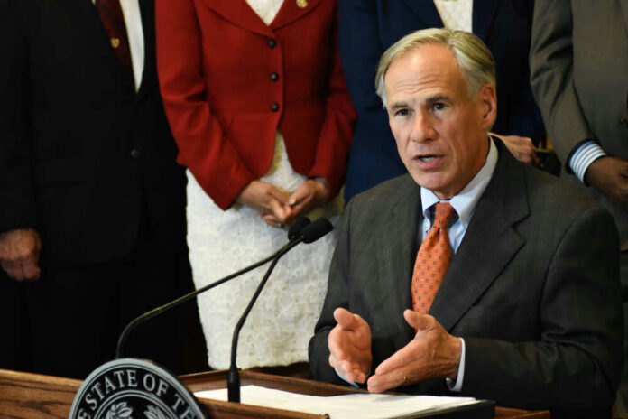 shutterstock_11277948501 Greg Abbott speaking at a podium with a microphone