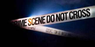 Police tape reading 'CRIME SCENE DO NOT CROSS' in a dark setting