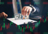 Businessperson holding a hundred-dollar bill over documents with stock chart overlay
