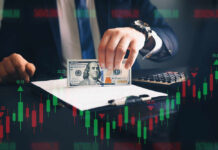 Businessperson holding a hundred-dollar bill over documents with stock chart overlay