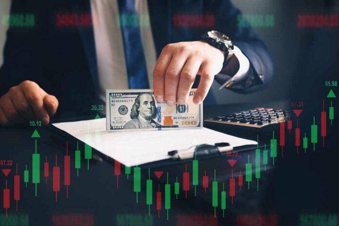 Businessperson holding a hundred-dollar bill over documents with stock chart overlay