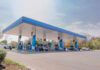 A modern gas station with fuel pumps and parked vehicles