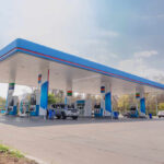 A modern gas station with fuel pumps and parked vehicles
