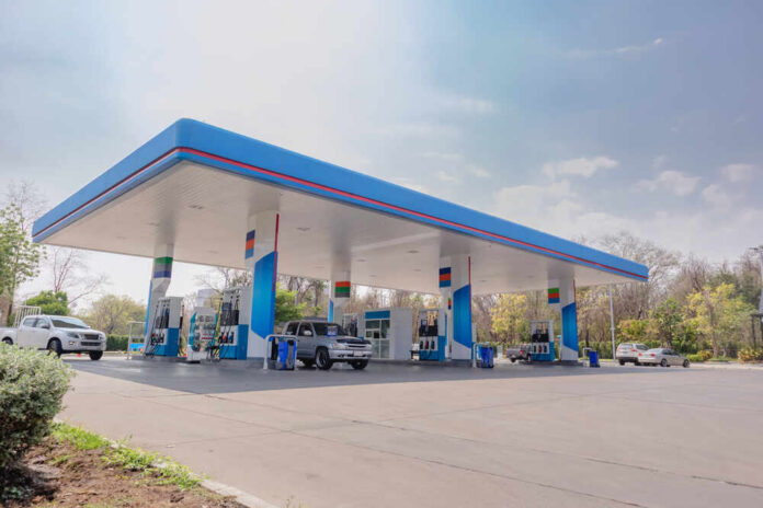 A modern gas station with fuel pumps and parked vehicles