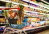 Shopping cart filled with various groceries in a supermarket aisle