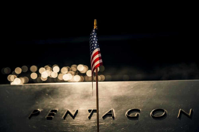 shutterstock_2321355077 American flag above engraved Pentagon sign at night
