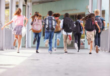 Children running with backpacks outside a school building.