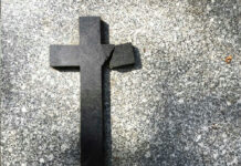 Broken black cross on a gray surface.
