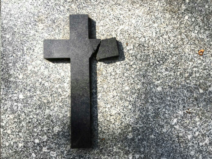 Broken black cross on a gray surface.