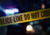 Kids’ Game Turns Deadly Police tape with blurred emergency lights in the background