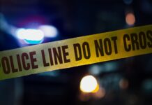 Police tape with blurred emergency lights in the background