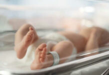 Newborn baby in hospital bassinet with ID band.