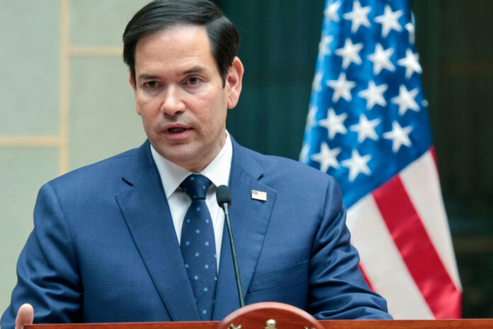 Marco Rubio speaking at a podium with a U.S. flag in the background