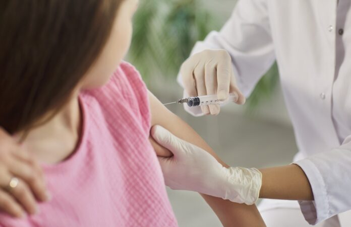 Healthcare worker gives a vaccine injection in a child's upper arm