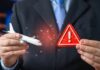 Businessperson holding airplane model and red warning sign