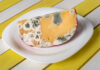Raw Cheese Scare – One Code Matters Moldy cheese wedge on a white plate