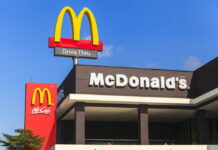 McDonald's restaurant exterior with drive-thru signs against blue sky