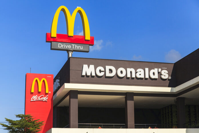 McDonald's restaurant exterior with drive-thru signs against blue sky